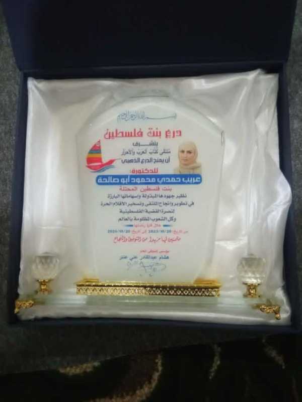 تسليمِ دِرعِ مُلتَقَىٰ كُتَّابْ ٱلعَرَبْ وَٱلأحرَٱرالذَّهبيِّ إلى المناضلةِ المجاهدةِ الدكتورةِ عُري